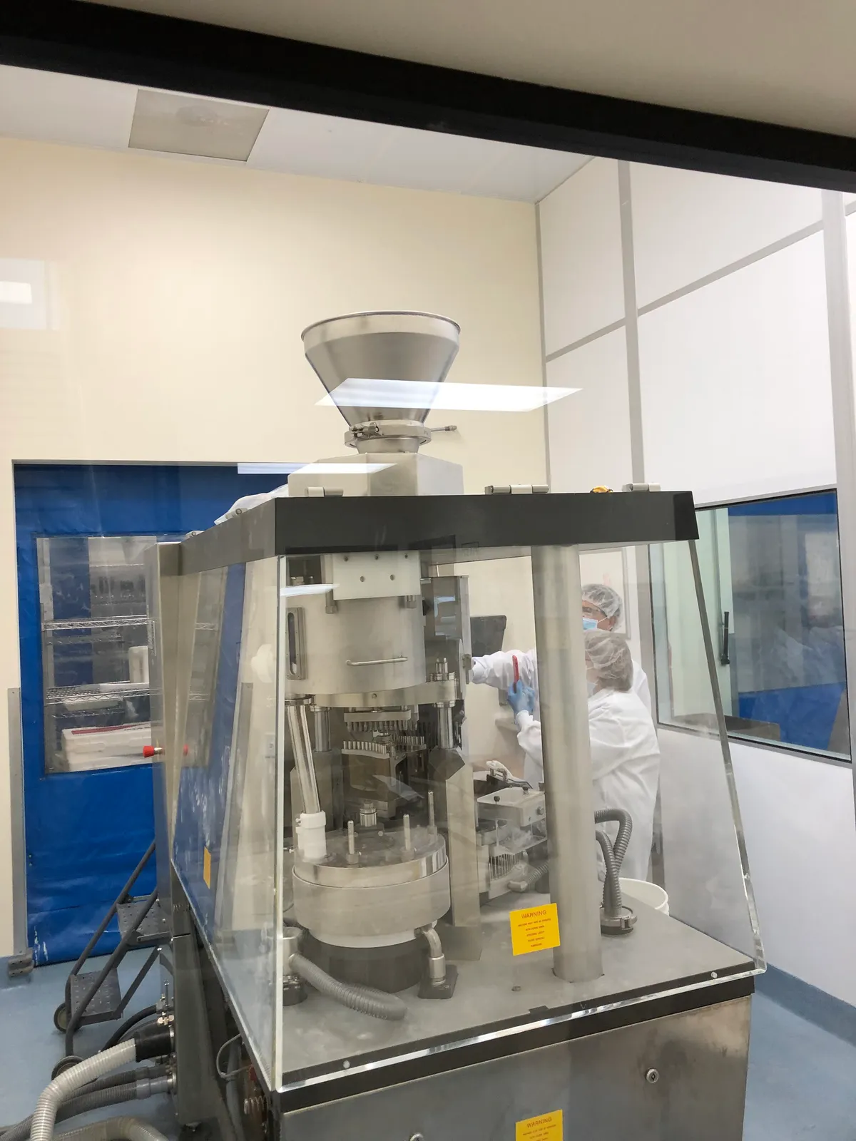 Capsule filling machine with a stainless feed hopper in a pharmaceutical cleanroom