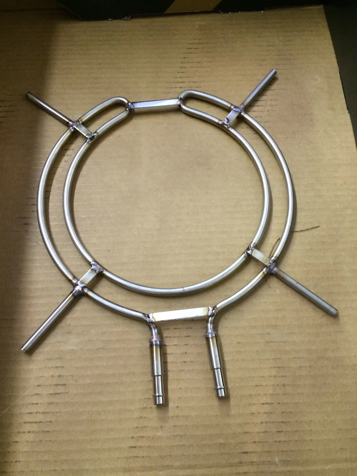 Bent and TIG welded stainless tube ring assembly laid out on cardboard