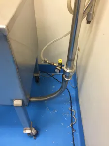 Stainless steel sanitary tubing run with an inline valve beside cleanroom equipment