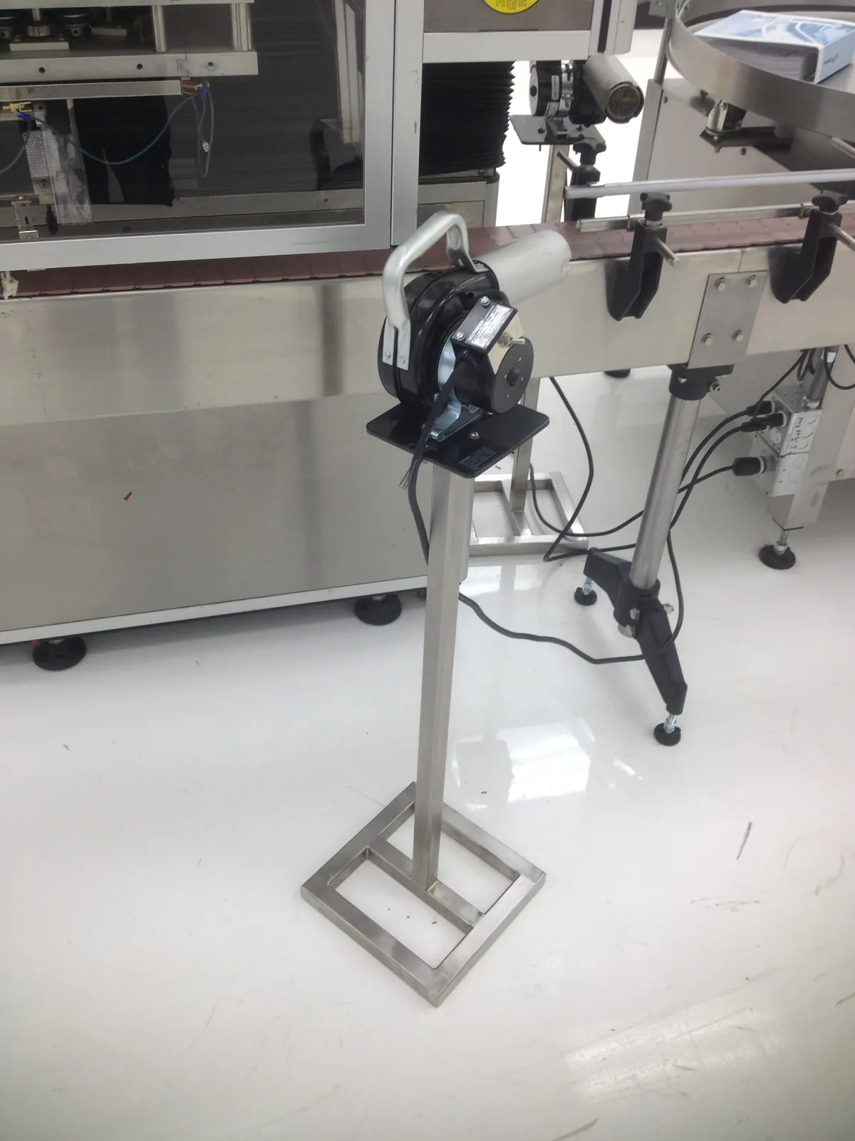 Stainless steel equipment stand with a welded square base on a production line