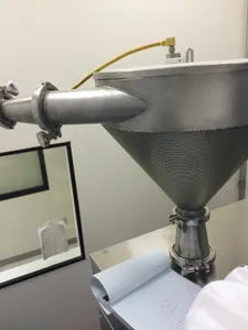 Side view of a stainless hopper with a perforated cone and tri-clamp outlet mounted on equipment