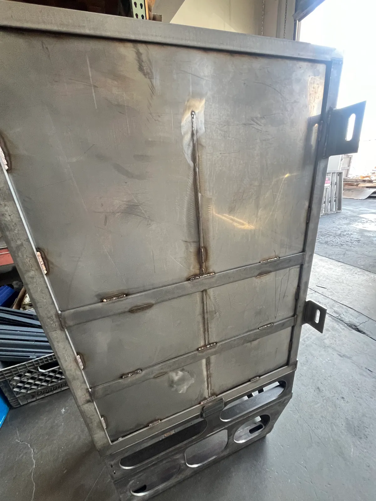 Large fabricated stainless steel frame panel with welded mounting brackets standing in the shop