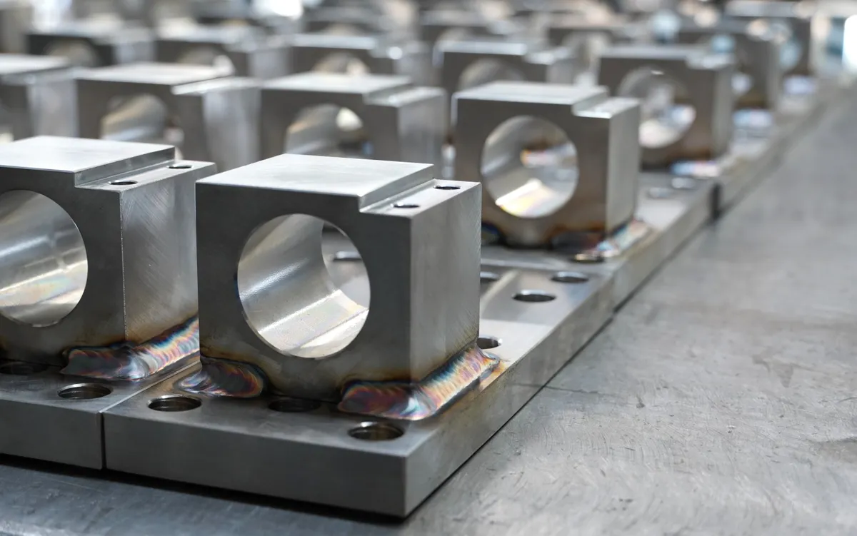 Production run of identical TIG welded stainless block-and-plate brackets lined up in the shop