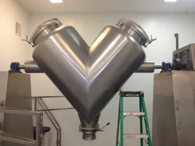 Stainless steel V-blender with sanitary clamp ports installed in a production room