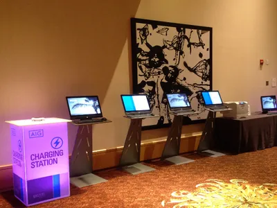 Custom fabricated laptop kiosk stands and an illuminated charging station set up for a corporate event