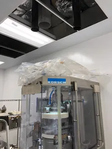 Tablet press being installed beneath stainless steel ceiling ducts in a cleanroom